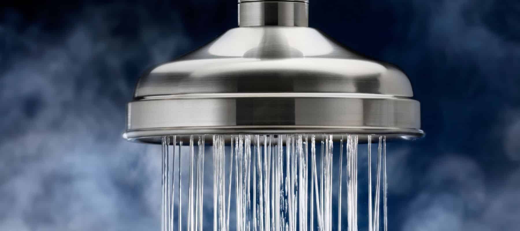 steam coming from a hot shower. Shower head with water flowing through it