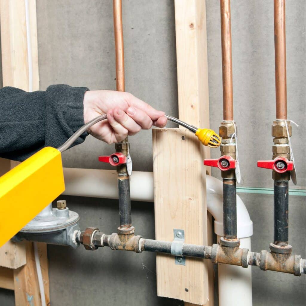 Gas line plumber using an tool to gauge if there is a gas leak
