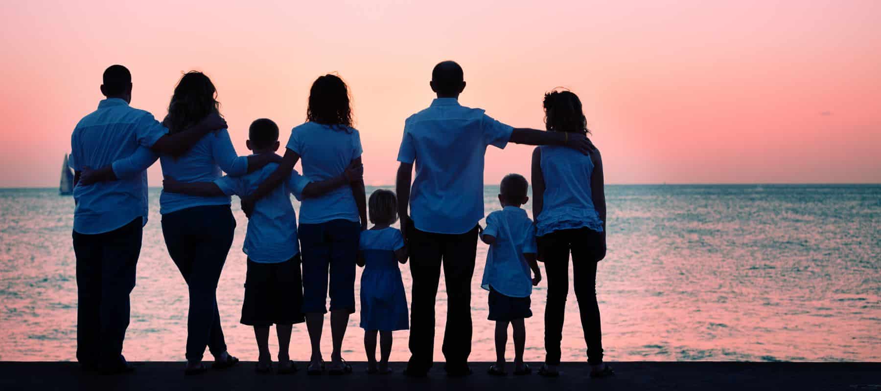 big family watching the sunset on a beach
