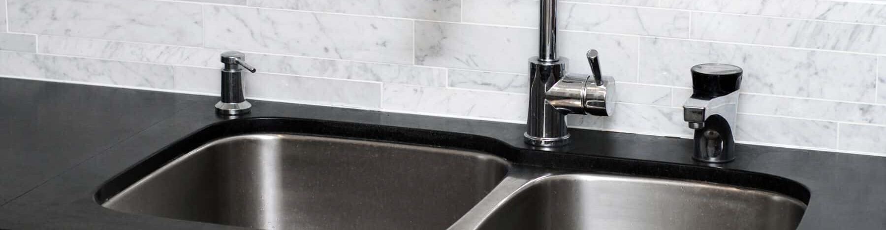 stainless steel kitchen sink with a black granite countertop