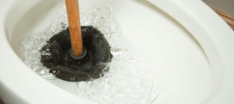 plunger in a toilet removing a clog
