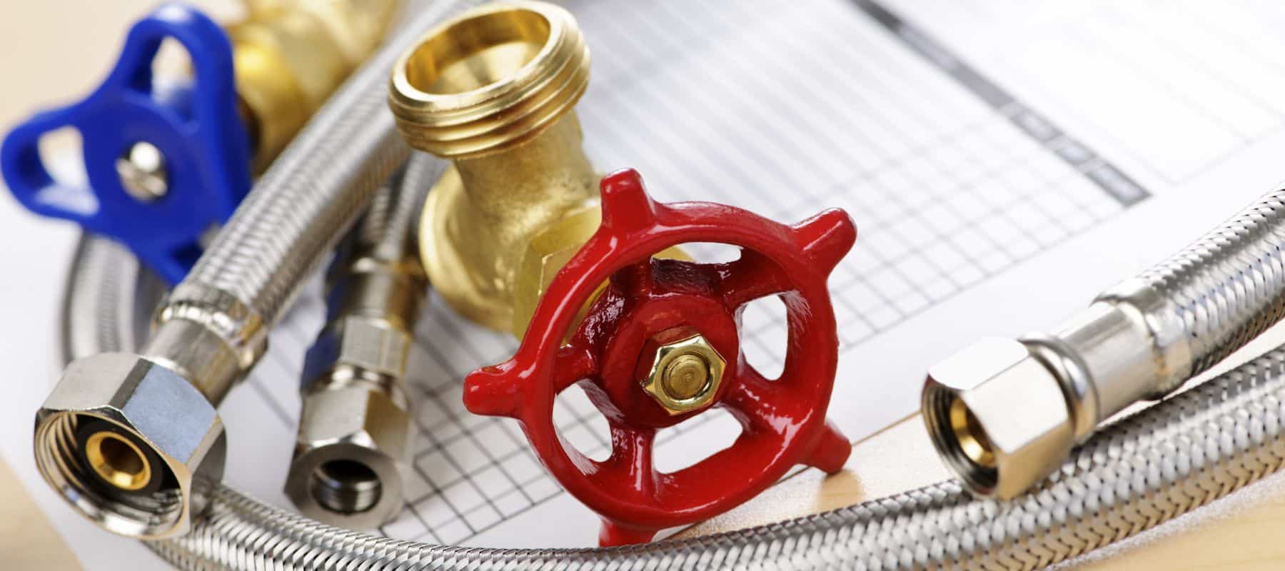 Close-up of various plumbing components, including a red valve handle, brass fittings, and flexible hoses, displayed on top of a maintenance checklist