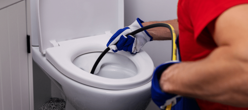 Plumber using a hydrojetting tool to unclog a toilet