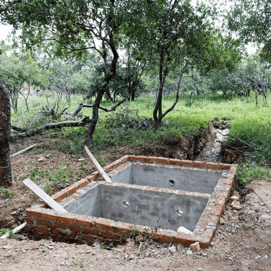 Brick and concrete septic tank under construction in a wooded outdoor area