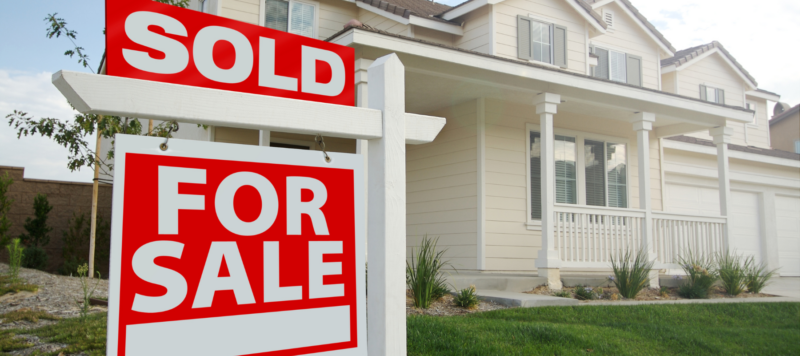 House with a sold real estate sign representing the importance of a sewer line inspection when purchasing a home.